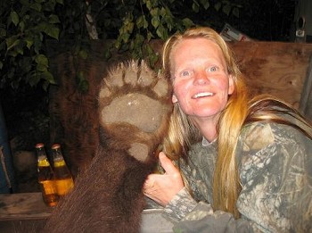 Woman poses next to giant black bear paw